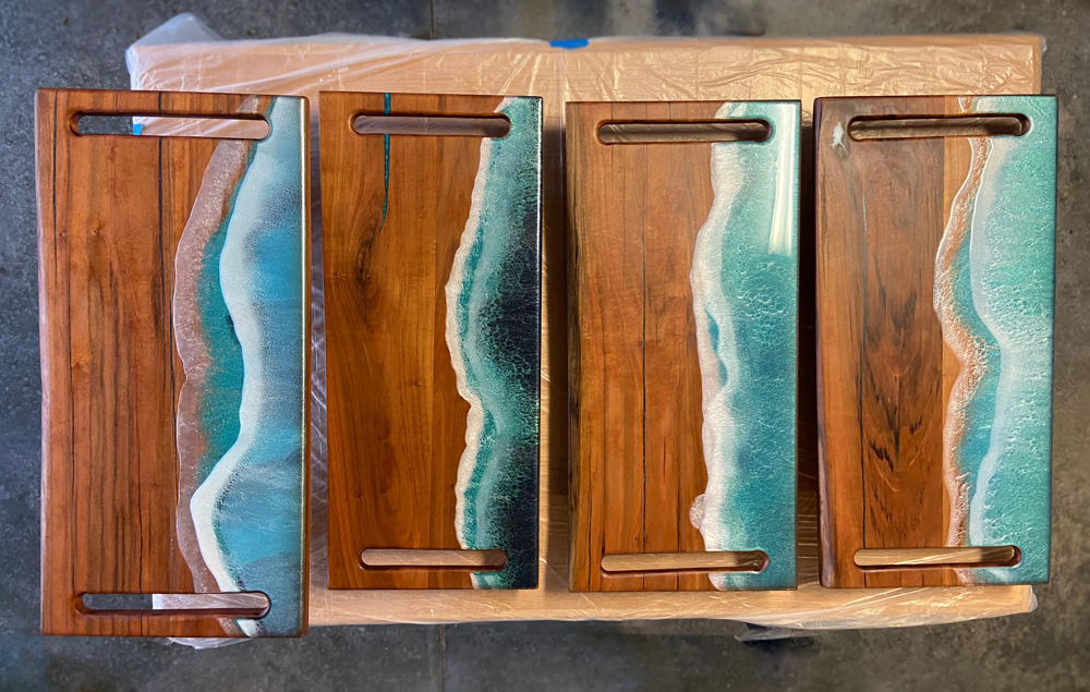 Four homemade charcuterie boards with cherry wood and epoxy designed to look like ocean waves