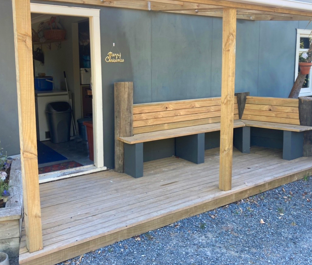 Covered porch with built-in benches built by Sam during the pandemic