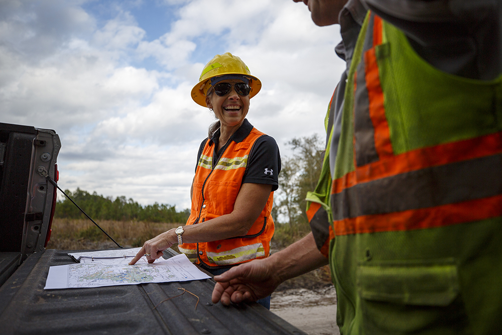 Forester smiling and pointing at map while in the field.