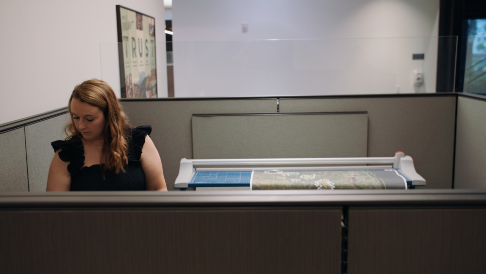 GIS analyst waiting at a printer in an office.